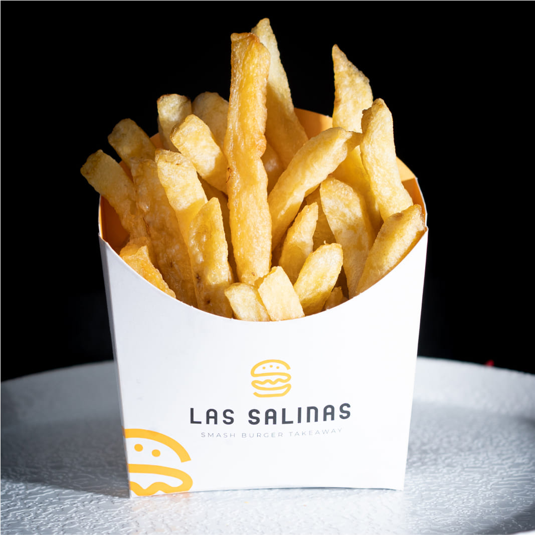 Patatas fritas caseras crujientes servidas en envase personalizado de Las Salinas Smash Burger en Cádiz